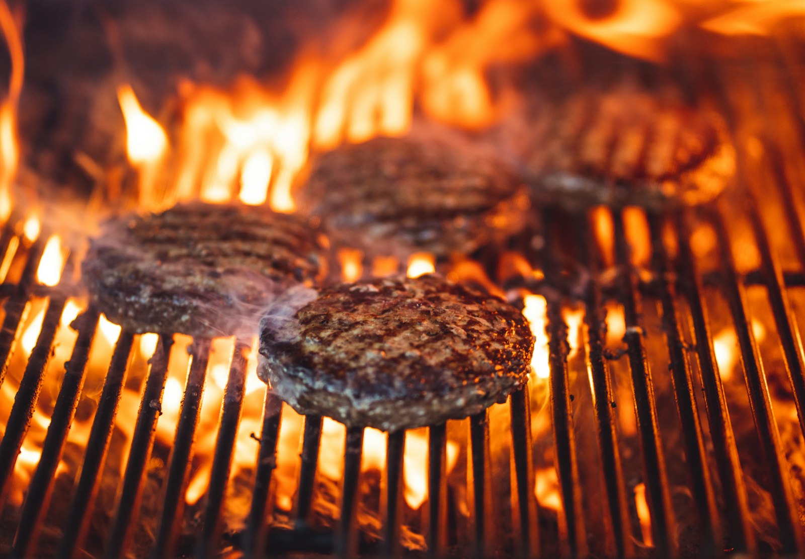 Carne sobre la parrilla con las llamas del encino atravesando la rejilla