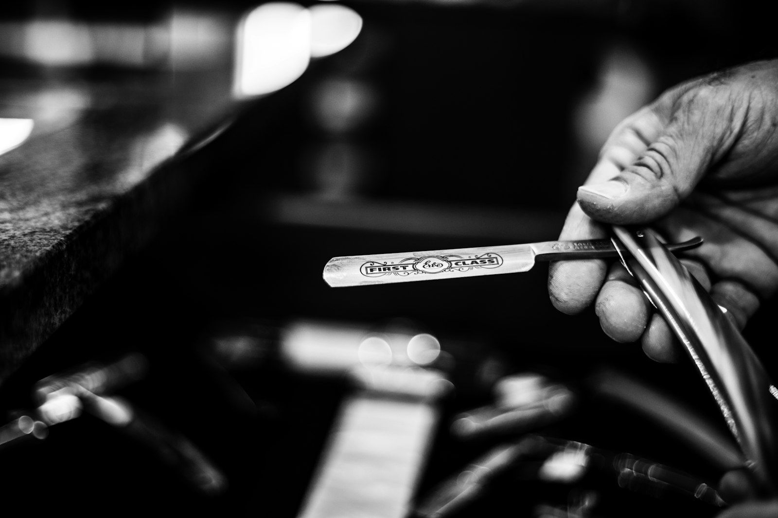 Mano de barbero sosteniendo una navaja barbera abierta